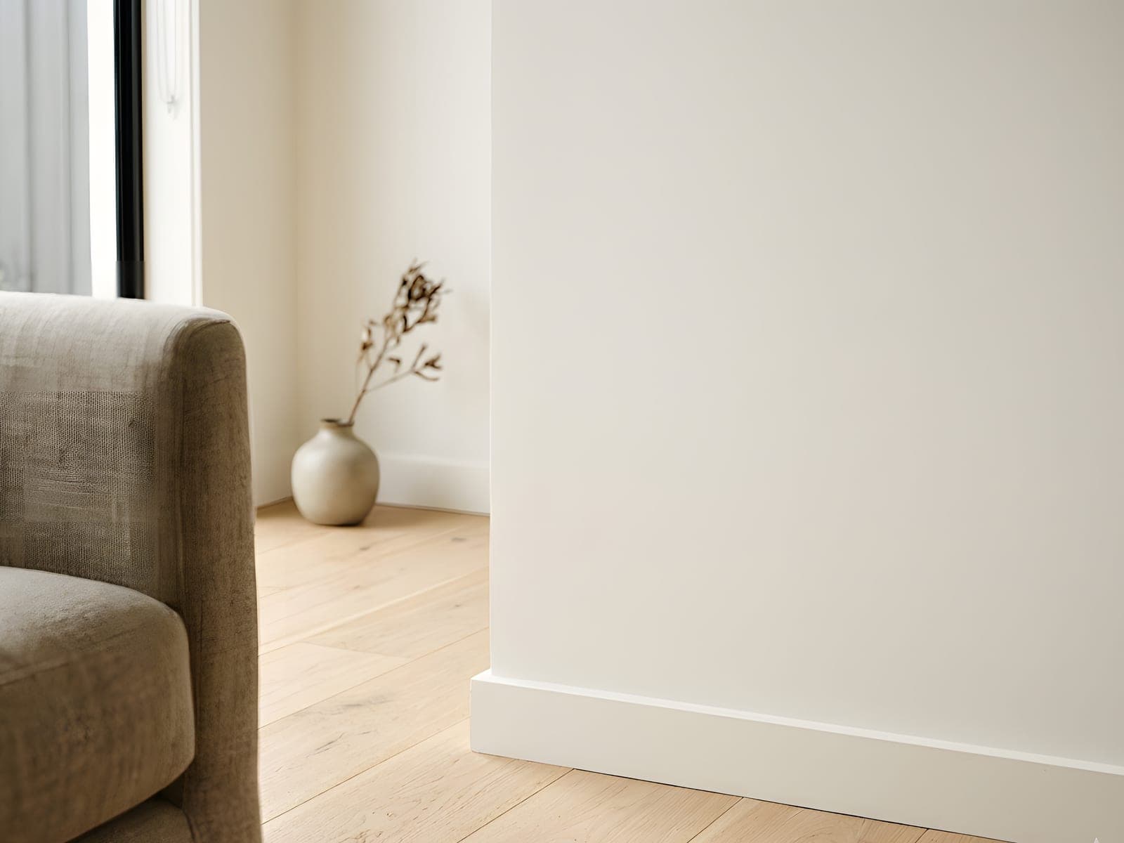 A close view of a flawless warm-white wall meeting light timber flooring
